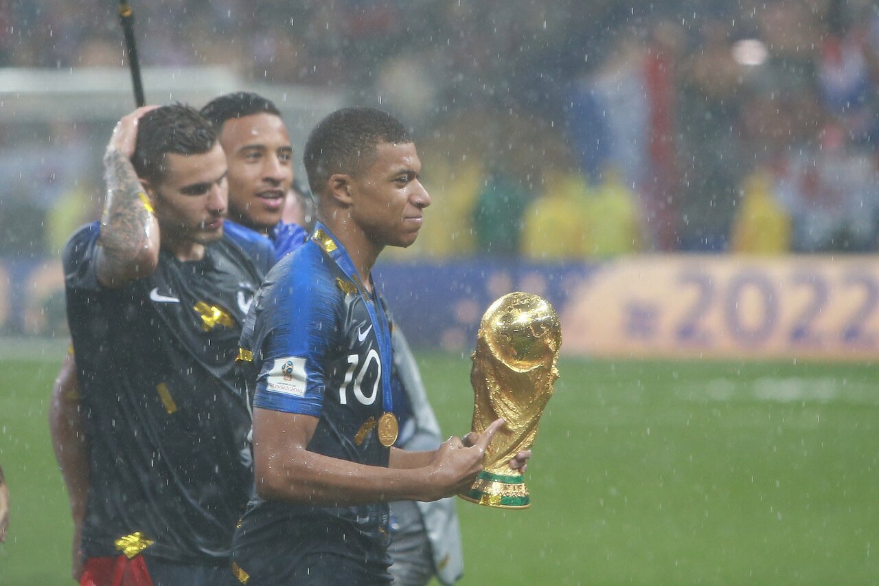 Kylian Mbappé carrying the World Cup trophy in the rain after the 2018 final